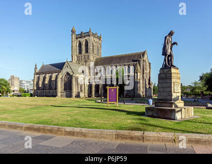 Paisley Abbey in Paisley Scotland UK seen from High Street in evening light with statue of Alexander Wilson right Stock Photo