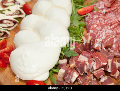 Mozzarella shaped braid on cutting board with salami and cheese. Stock Photo