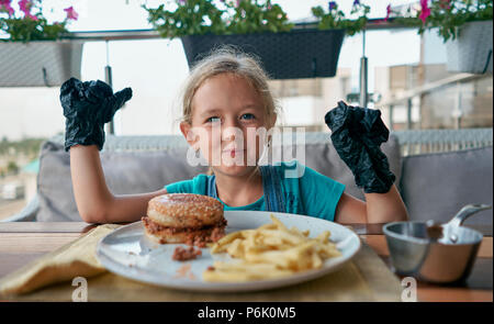 child eats a Burger in a restaurant Stock Photo