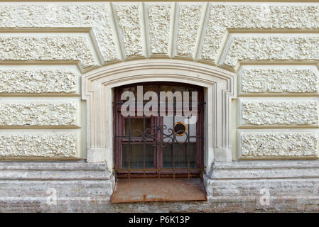 The window closed with a grating with ventilation on the facade of the old house Stock Photo