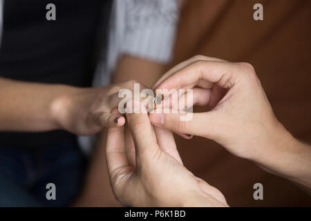 Close up of man putting wedding ring on woman finger Stock Photo