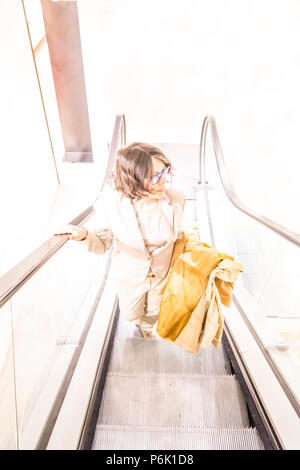 Woman with Overcoat Hanging on Her Arm in an Escalator. Stock Photo