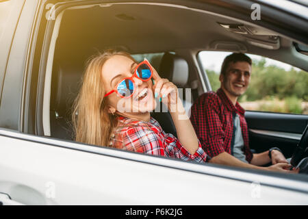 Happy young woman in the car with her husband is happy with glasses Stock Photo