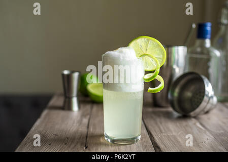 Egg Gin Fizz Cocktail with Lime Garnish. Making Gin Fizz Drink with ingredients, copy space. Stock Photo