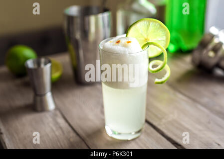 Egg Gin Fizz Cocktail with Lime Garnish. Making Gin Fizz or Pisco Sour Drink with ingredients, copy space. Stock Photo