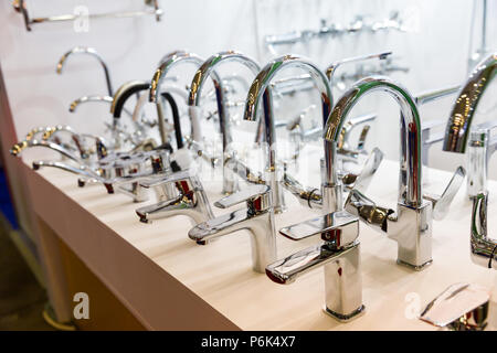 Rows of new chrome faucets in plumbing shop, closeup. Sanitary equipment Stock Photo