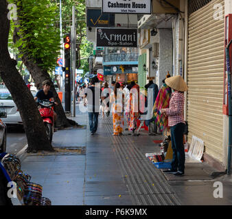 Saigon, Vietnam--March 19, 2016.  A  busy luxury shopping street in Saigon; a street merchant displays merchandise for sale. Stock Photo