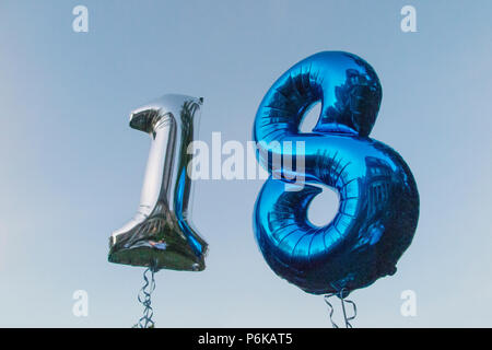 Two helium balloons celebrating an 18th Birthday party against a blue sky at dusk Stock Photo