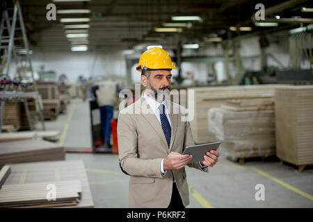 Portrait of middle-aged businessman with digital tablet in factory Stock Photo