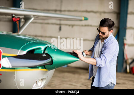 Handsome young pilot checking airplane  in the hangar Stock Photo