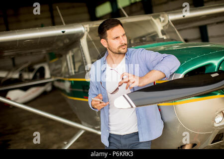 Handsome young pilot checking airplane  in the hangar Stock Photo