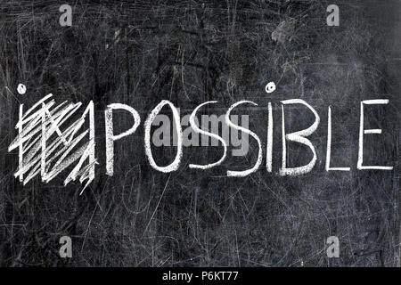 Impossible becomes possible handwritten with white chalk on dirty blackboard Stock Photo