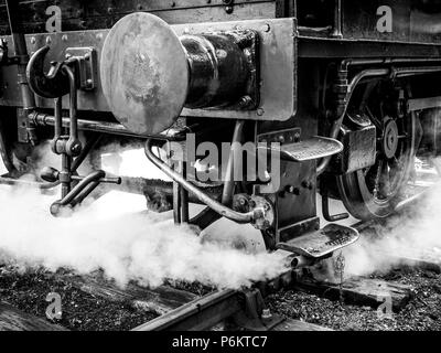 Monotone close frontal shot of a steam locomotive at the Mid Suffolk Light Railway, showing buffer and couplings emerging from light steam Stock Photo