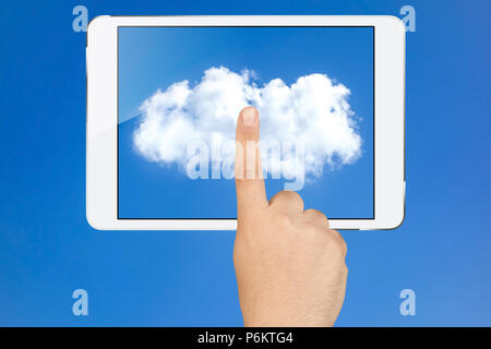 Male hand touching cloud on screen of electronic tablet pc in landscape orientation against clear blue sky Stock Photo