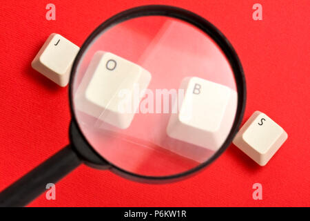Jobs word made with keyboard keys under magnifier lens against red Stock Photo
