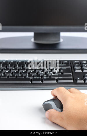 Closeup of Male hand on wireless mouse black desktop computer keyboard and display Stock Photo