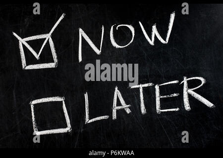 Now and Later check boxes handwritten with white chalk on blackboard Stock Photo
