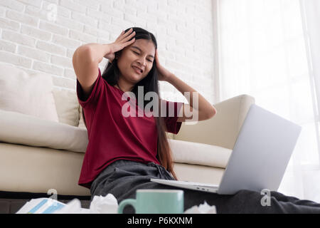 Asian woman freelancer stress emotion while working with laptop and paperwork at sofa in living room in house.work at home concept Stock Photo