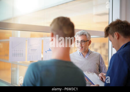 Teacher in classroom teaching economics to young people Stock Photo