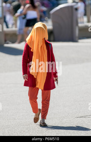 Woman with face obscured, covering the face with scarves, veils and masks in Blackpool, Lancashire, 1st Jul, 2018. UK Weather: Sunny sweltering day at the coast as sun worshippers & tourists enjoy spell on the beach & seafront promenade Stock Photo