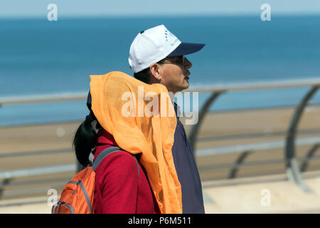 Woman with face obscured, covering the face with scarves, veils and masks in Blackpool, Lancashire, 1st Jul, 2018. UK Weather: Sunny sweltering day at the coast as sun worshippers & tourists enjoy spell on the beach & seafront promenade Stock Photo