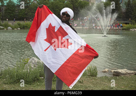 Canada Day. Man holds Canadian flag after getting turban tied at Turban, Eh?, an event hosted by the World Sikh Organization at Prince's Island Park in Calgary on Canada Day. People were invited to have a red or white turban wrapped around their head and learn about the Sikh culture. Rosanne Tackaberry/Alamy Live News Stock Photo