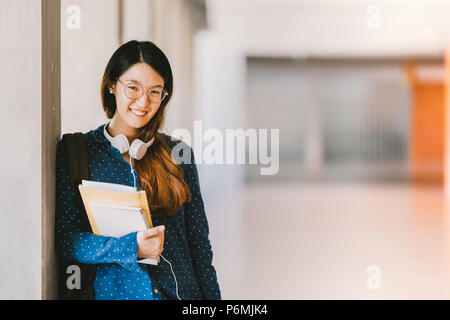 Young beautiful Asian high school girl or college student wearing eyeglasses, smiling in university campus with copy space. Education concept Stock Photo