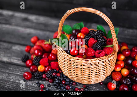 Fresh forest berries in basket on wooden table. Copy space Stock Photo