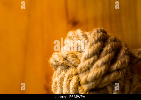 fender - marine knot of thick brown rope on a wooden background, closeup Stock Photo