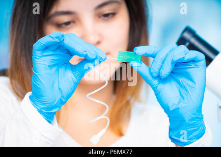 technician girl with microfluidic device LOC in microbiological lab Stock Photo