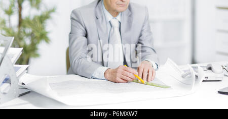senior engineer works with drawings sitting at his Desk Stock Photo
