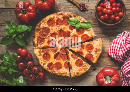 Homemade pepperoni pizza on old rustic wooden table. Top view, toned image Stock Photo