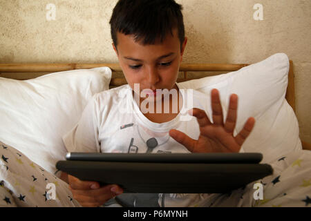 11-year-old boy playing with a digital tablet in Salento, Italy. Stock Photo