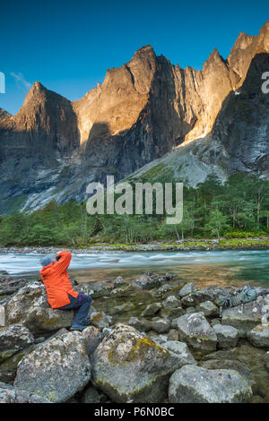 Outdoor photographer taking pictures of Trollveggen, or the Troll Wall, in early morning light in Romsdalen valley, Møre og Romsdal, Norway. Stock Photo