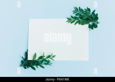 Desktop mock-up with blank paper card, branch on white shabby table background. Empty space. Styled stock photo, web banner. Flat lay, top view. Stock Photo