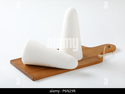 two white sugar loaves or cones on wooden cutting board Stock Photo