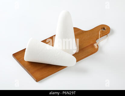two white sugar loaves or cones on wooden cutting board Stock Photo