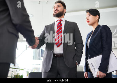 Businessman in suit shaking hand to his partner at office Stock Photo