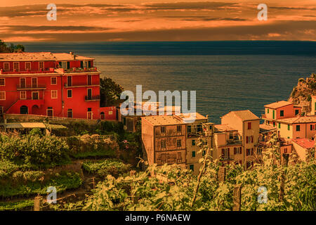 sunset on colorful houses overlooking deep blue sea in Italy Stock Photo
