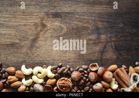 Different nuts on a wooden table. Cedar, cashew, hazelnut, walnuts and a spoon on the table. Many nuts are inshell and chistchenyh on a wooden backgro Stock Photo
