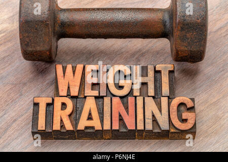 weight training - word abstract in vintage lettepress wood type printing blocks with an old dumbbell Stock Photo