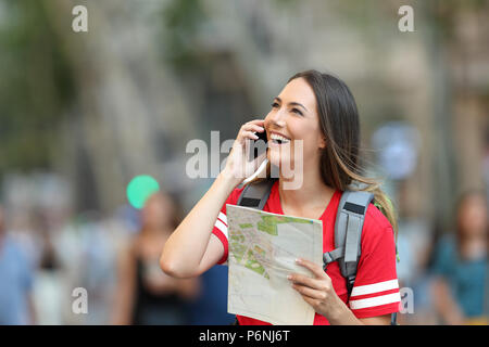 Happy teen tourist calling on phone in the street and looking above Stock Photo