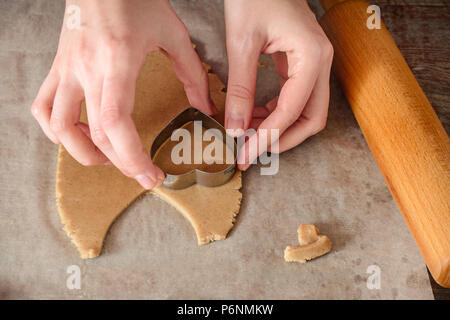 Homemade ginger biscuit cooking, womans hands cut out dough in the shape of heart Stock Photo
