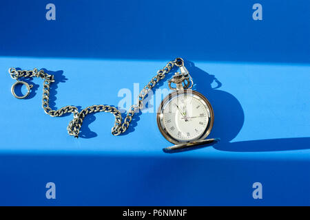 Vintage pocket watch on chain on blue background Stock Photo