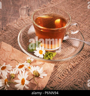 Cup of medicinal herbal chamomile mint tea on a wooden desk. Rustic style background Stock Photo