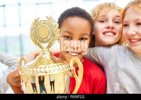 Multicultural sporty children team is happy about a winner cup Stock Photo