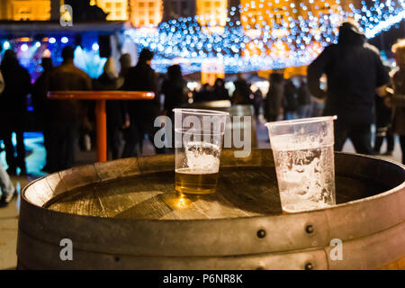 Two plastic glasses of beer surrounded by crowd. Half empty. Stock Photo