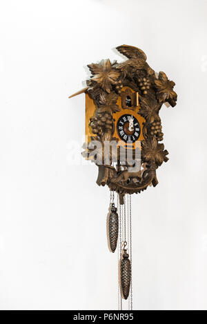 Old brown wooden cuckoo clock, on a white wall. Stock Photo