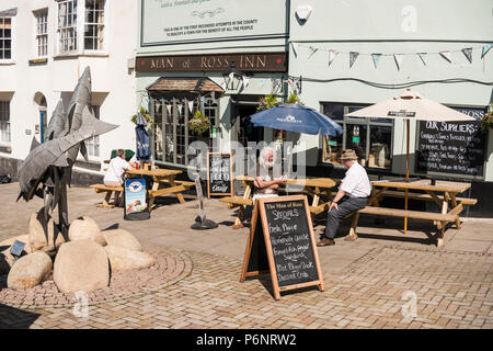 People sitting outside of Man of Ross Inn pub and enjoying drinks and sunny weather, Wye Street, The Man of Ross Inn, Ross on Wye, Herefordshire, UK Stock Photo