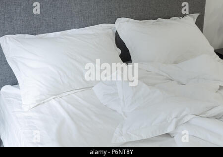 Detail in bedroom, an empty bed, white pillow and blanket close up, crumpled bedding, morning rush in hurry. Stock Photo